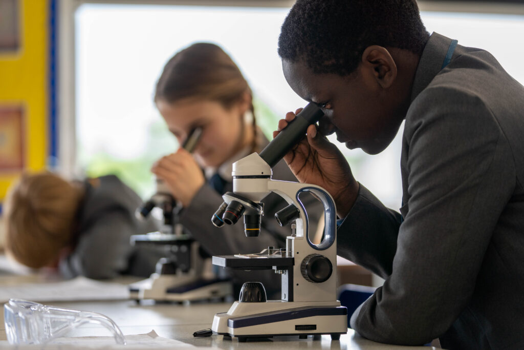 A young student looking down a microscope