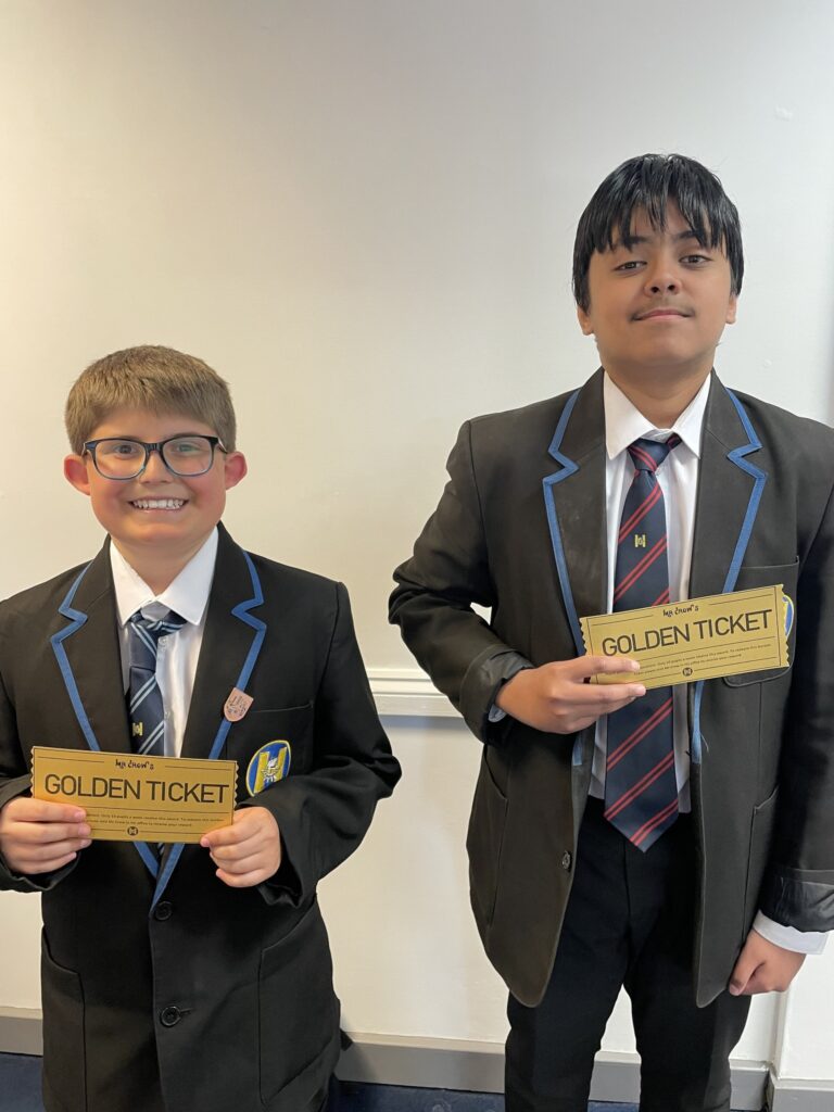 Two boys smiling for a photo, each holding a 'golden ticket'.
