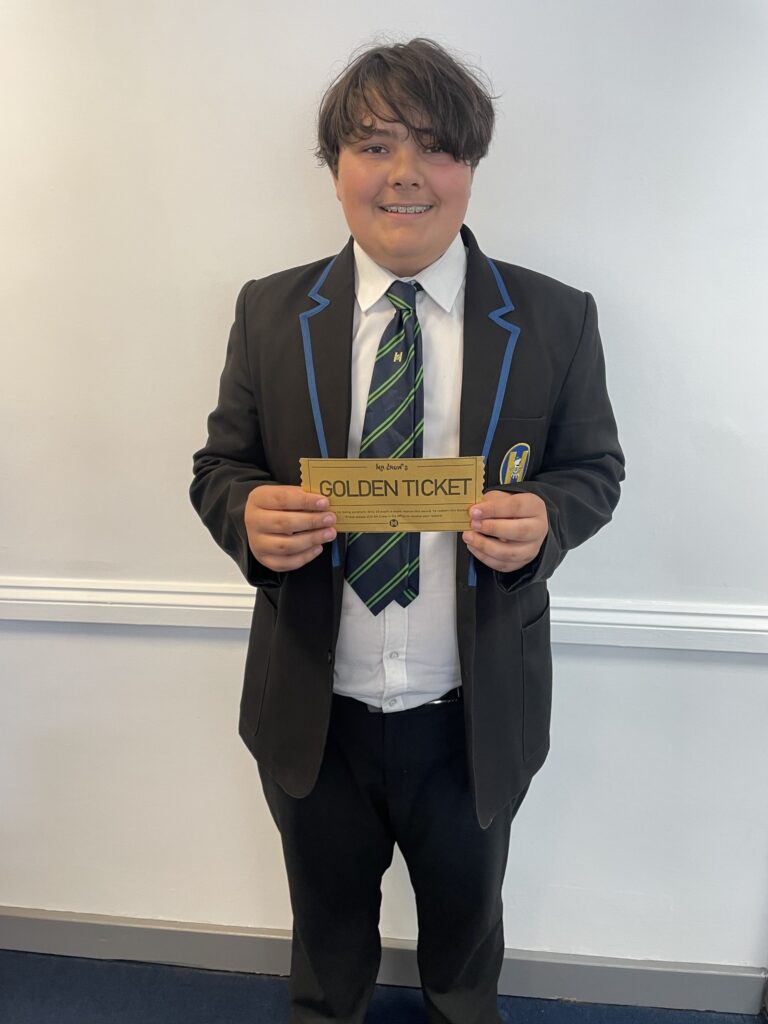 A boy smiling for a photo holding a 'golden ticket'.