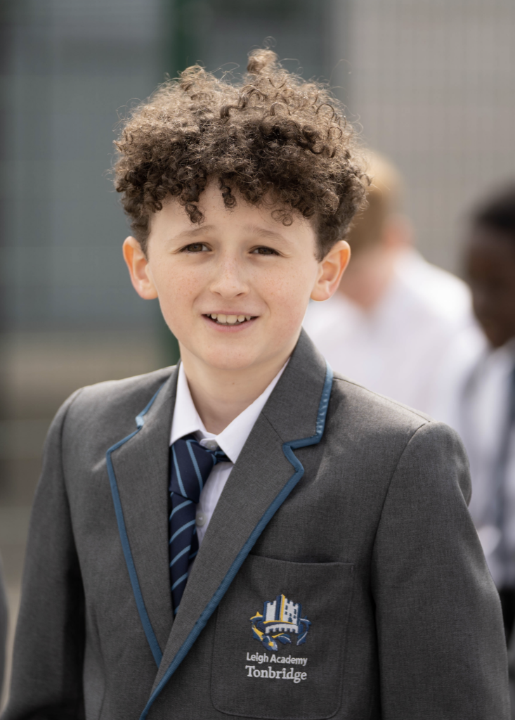 A male Year 7 student is pictured looking directly at the camera and smiling, whilst wearing his academy uniform.
