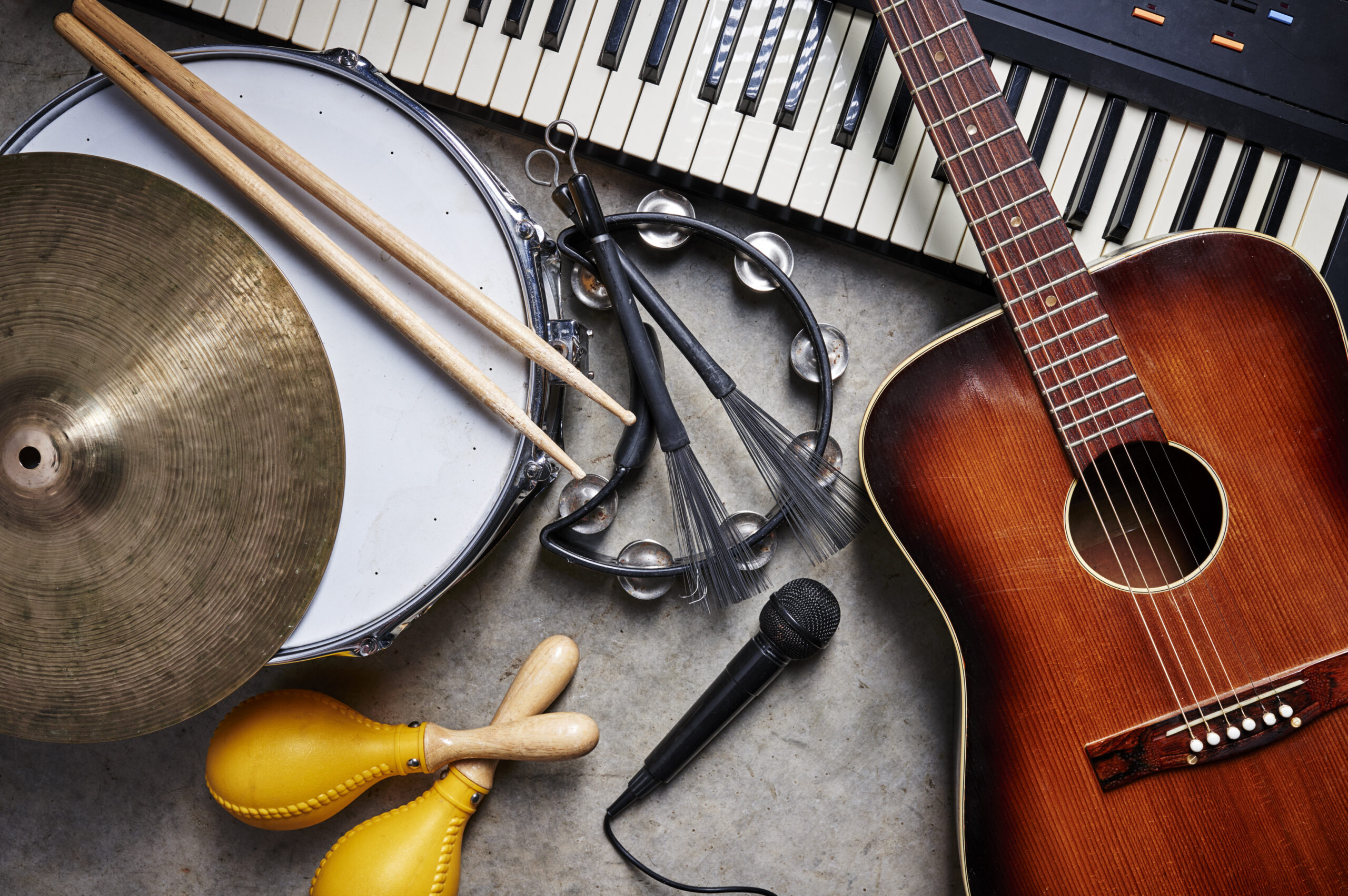 A selection of different musical instruments seen laid out on the floor. The instruments include a guitar, maracas and a tambourine.