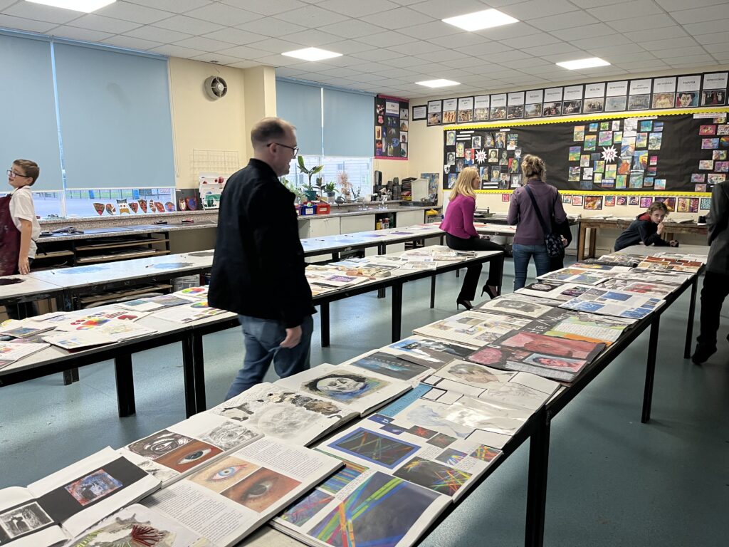 Parents/carers are pictured visiting a display of some artwork created by students at an Open Day at the academy.