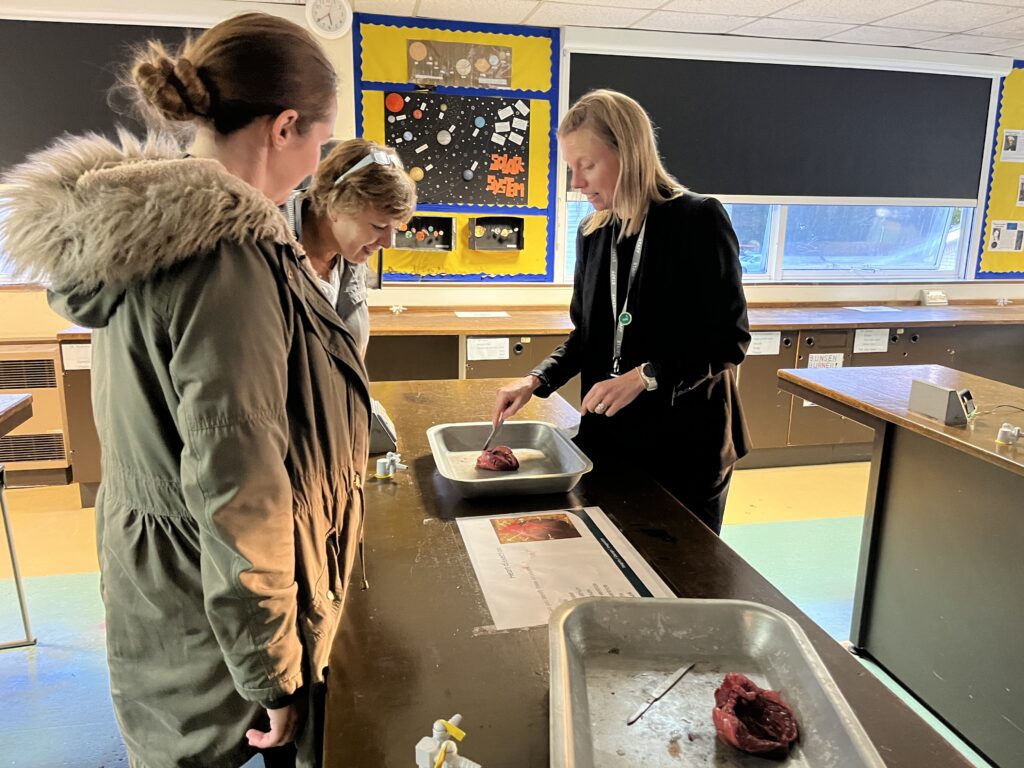 Parents/carers are pictured watching a demonstration by a member of staff in a Science lab in the academy building, during an Open Day.